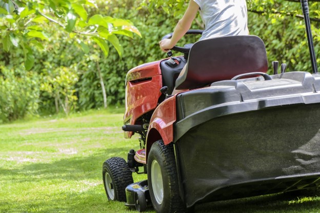 A riding lawnmower in action cutting a healthy lawn