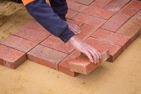 Laying bricks for a hardscaping surface.