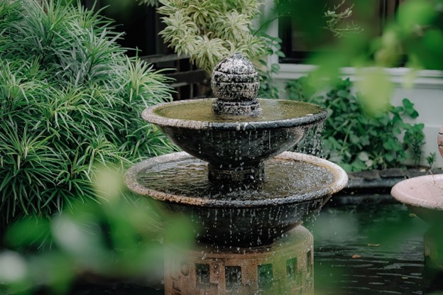 An intricate fountain surrounded by greenery.